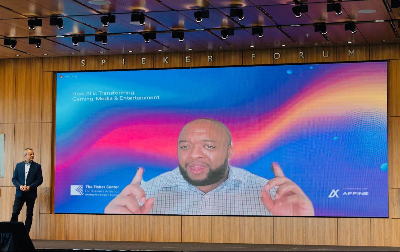A presenter stands beside a large screen showing Christopher Lafayette speaking remotely, with Fisher Center and Affine logos below.