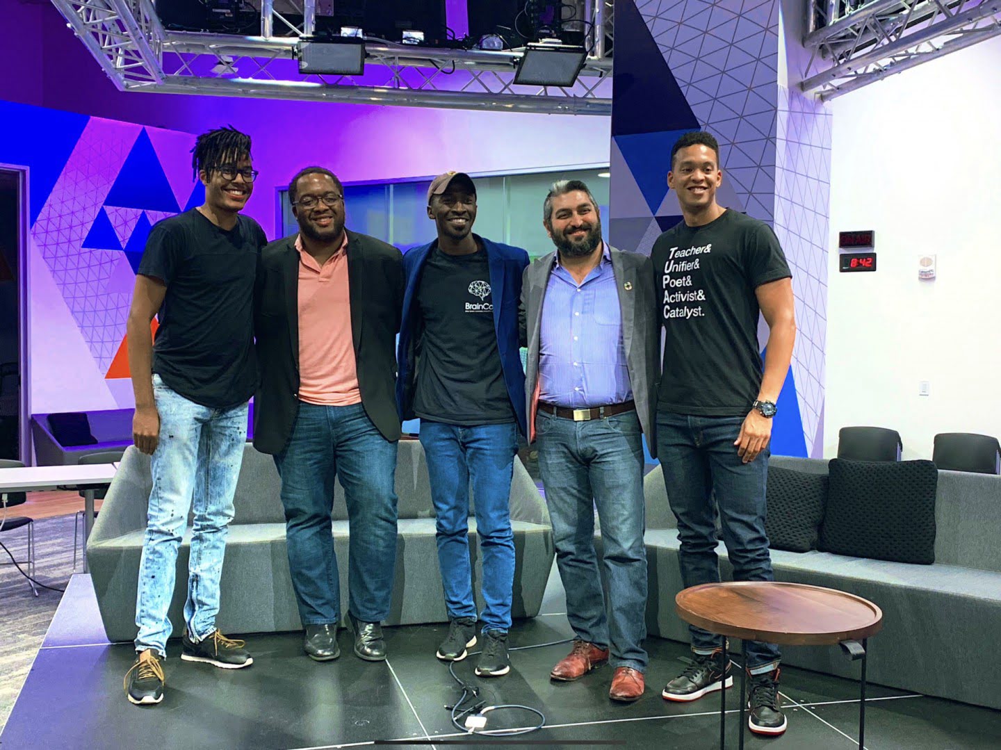 Five panel participants stand together in front of a purple illuminated geometric wall at Microsoft Reactor in San Francisco.