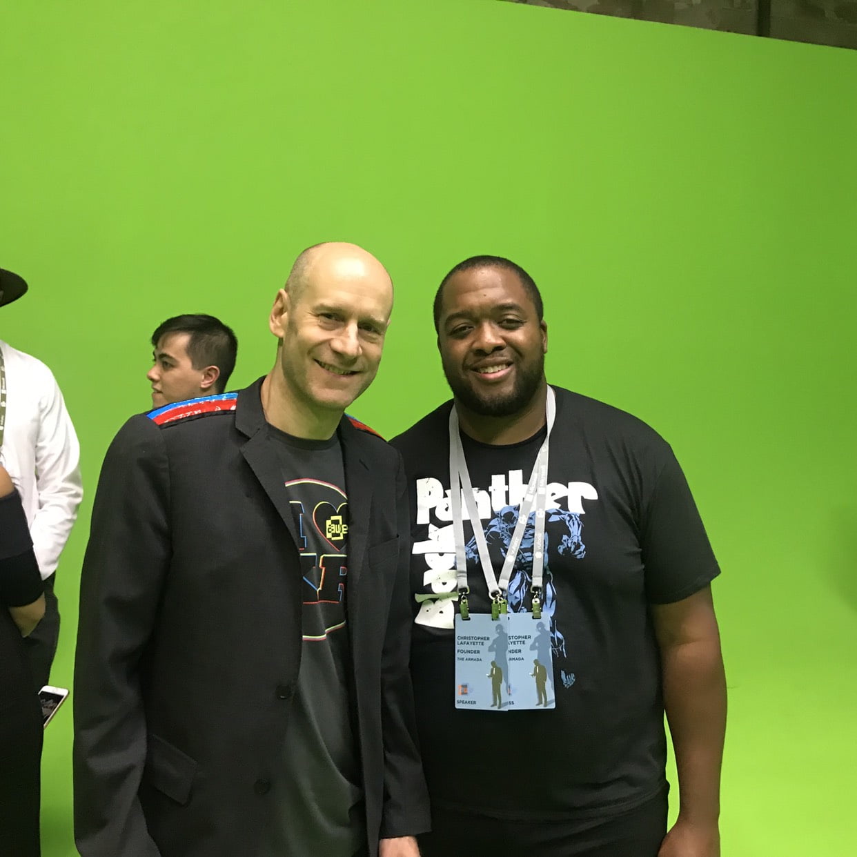 Christopher Lafayette and a fellow attendee standing in front of a green backdrop; Christopher’s badge shows a former venture affiliation.