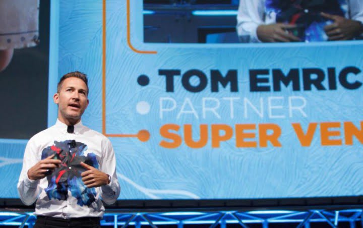 Original VRScout article photograph of Tom Emrich speaking on a stage.