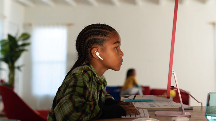 A child wearing earphones and working at a desktop computer.